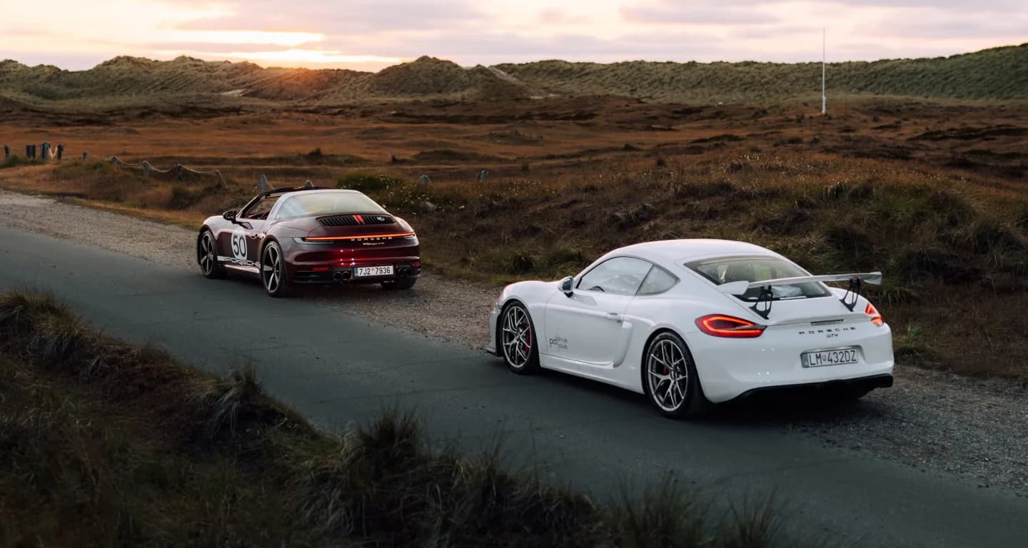 Two sports cars on a coastal road at sunset