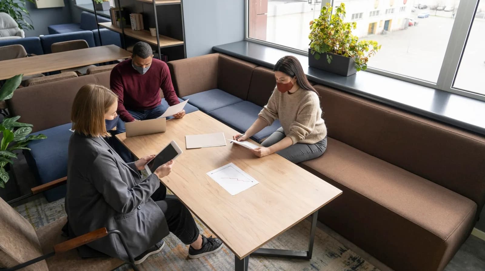 Three colleagues working around a table in a co-working lounge
